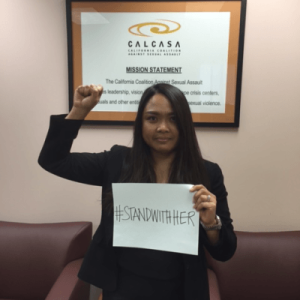 Imleda Buncab holding a sing saying "#StandWIthHer"