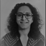 Black and white photo of a women with glasses and curly hair smiling