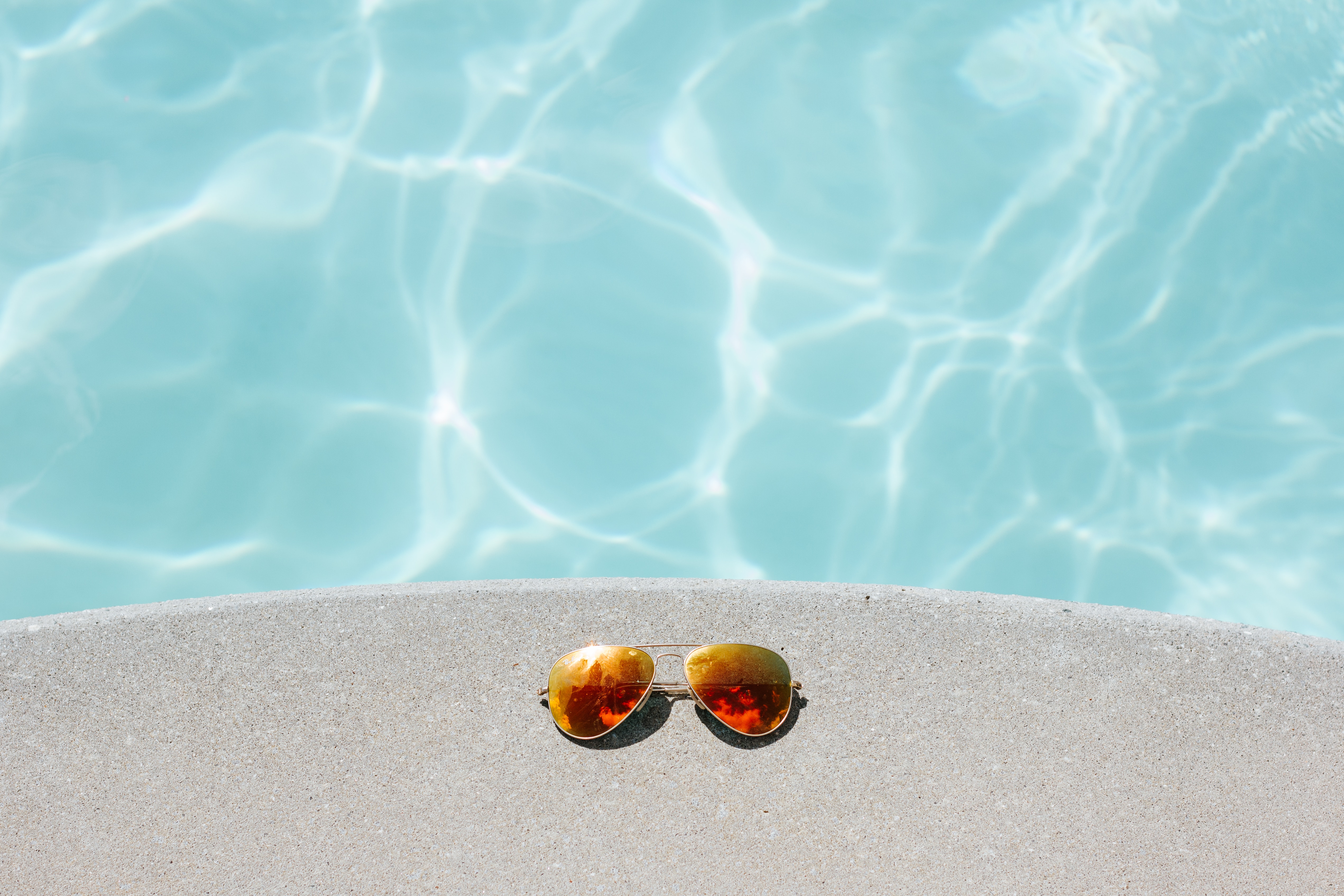 Image of sunglasses sitting on the ledge by the pool