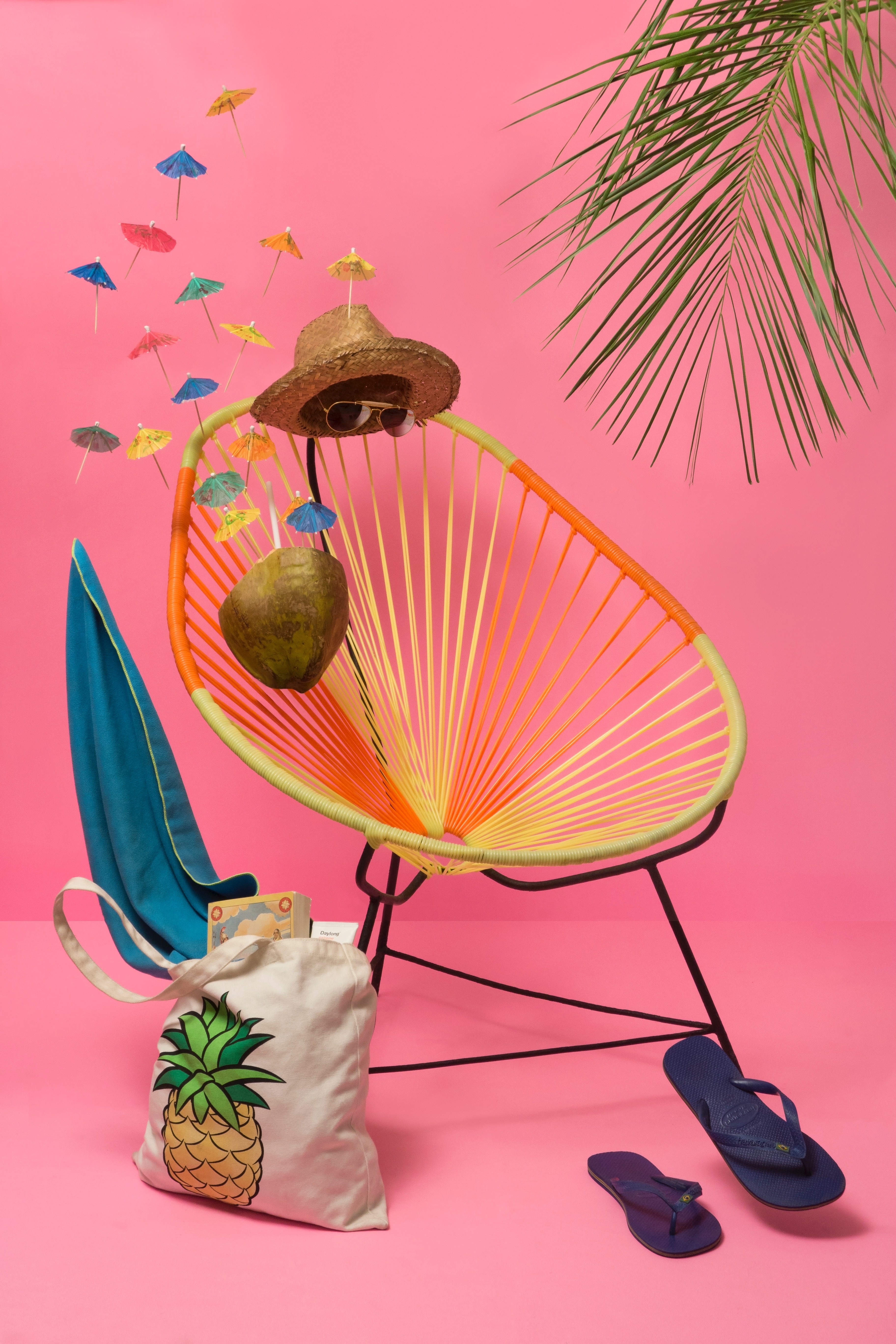 Photo of a circular lounge chair with floating sunglasses, a hate, a coconut drink, and flip flops like an invisible person is sitting in the chair