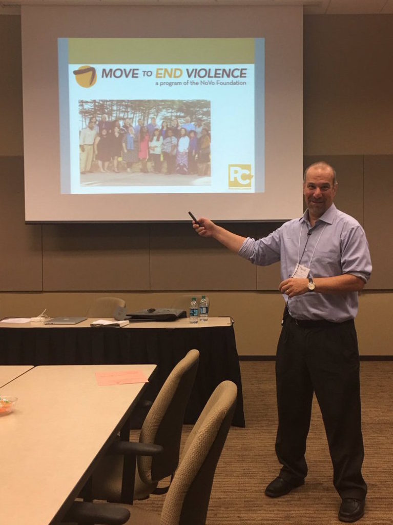 David Lee, bearded white man with short hari pointing at a screen showing Move to End Violence