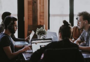 employees sitting at table with laptops in office environment